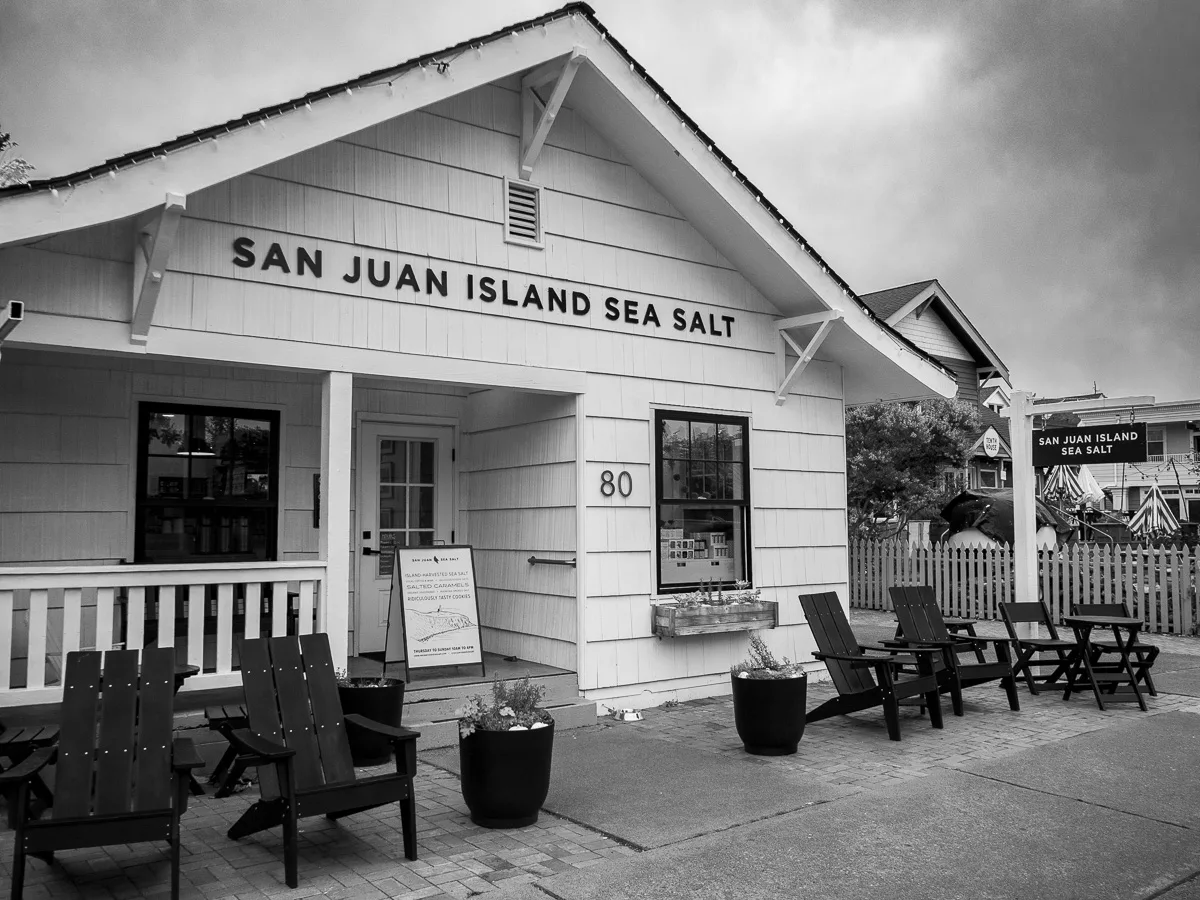 San Juan Island Sea Salt white storefront building with picnic benches and chairs, black and white photograph