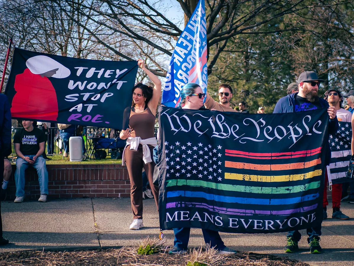 People holding large protest banners, including “We the People Means Everyone” and “They Won’t Stop at Roe”
