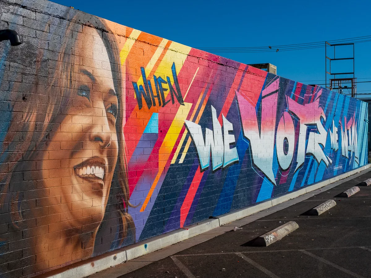 Your Voice Matters: Vibrant street mural in Las Vegas featuring a joyful face with blue-streaked hair against geometric patterns