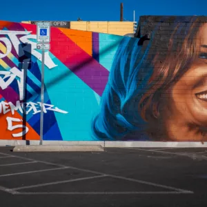 Your Voice Matters: Vibrant street mural in Las Vegas featuring a joyful face with blue-streaked hair against geometric patterns