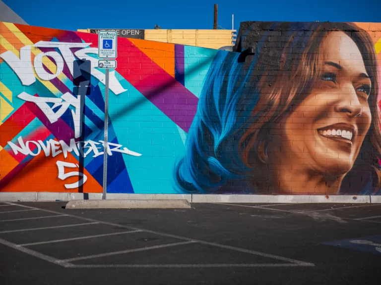 Your Voice Matters: Vibrant street mural in Las Vegas featuring a joyful face with blue-streaked hair against geometric patterns